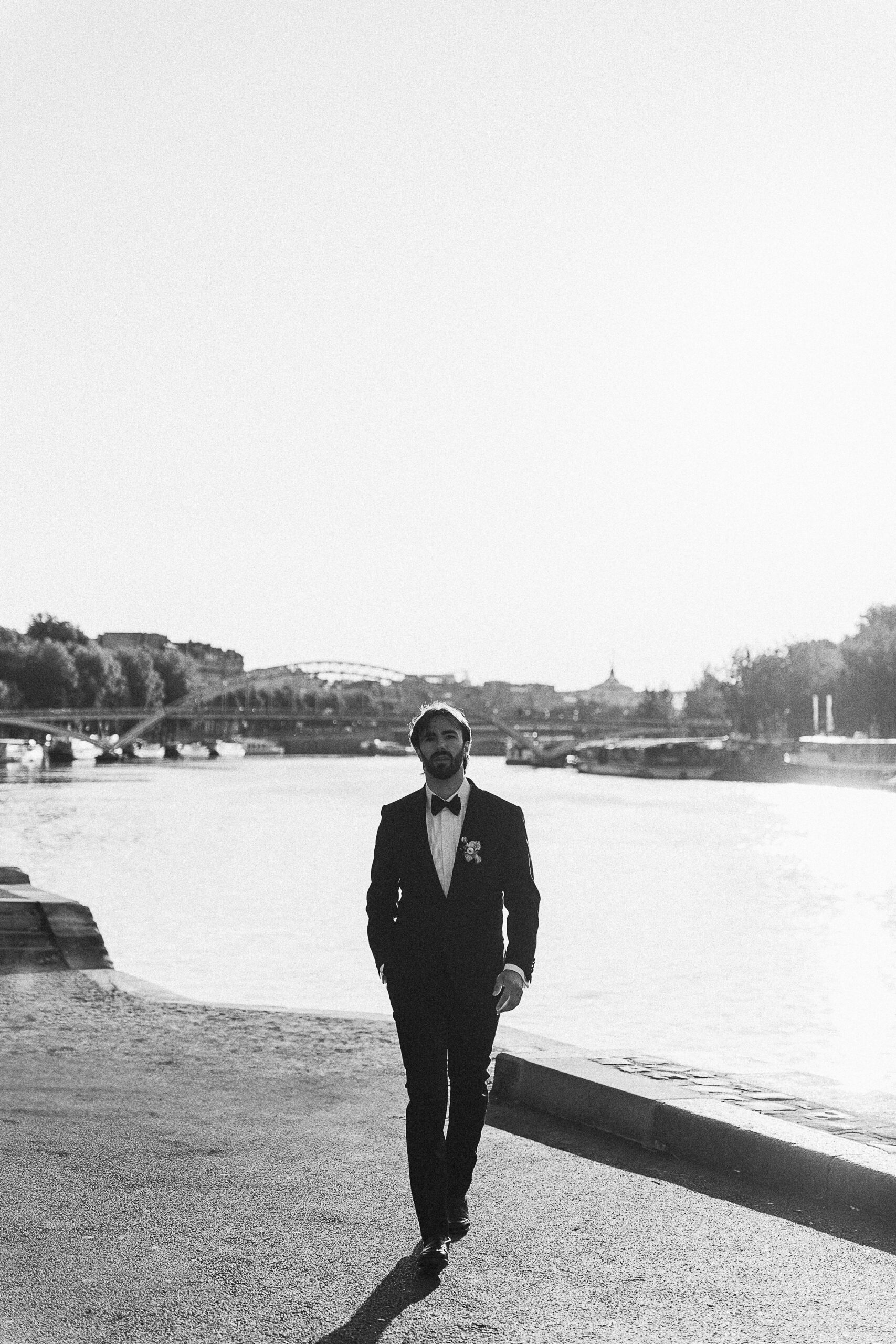 The groom walking on the banks of the Seine near the Eiffel Tower