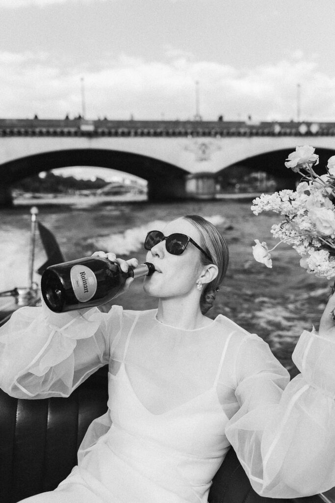 the bride drinking Ruinart from a bottle on a French Riviera-style boat on the Seine river in Paris